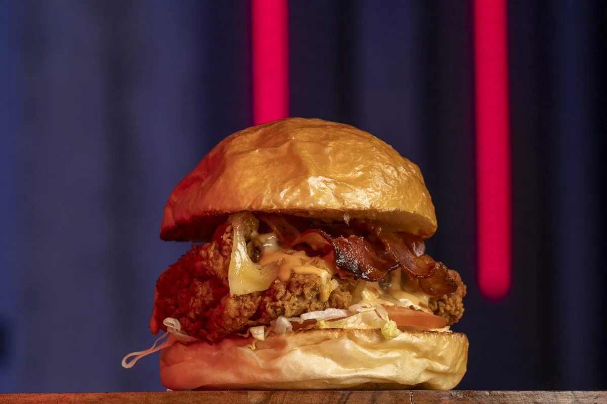 Hamburguesa La CBD: chicken Bacon Deluxe: contramuslo de pollo rebozado, lechuga, tomate, queso monterrey, bacon crujiente, salsa Chick Addiction y cebolla crispy