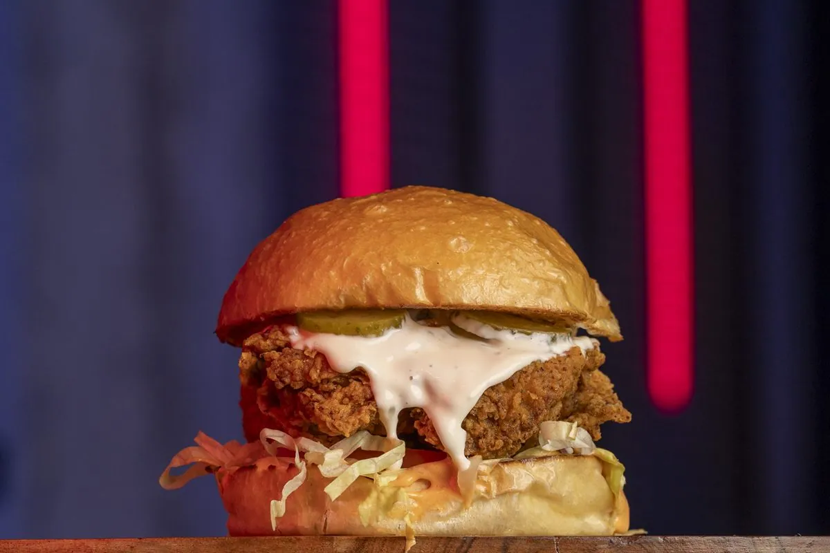 Hamburguesa La Kimchi Crunch: contramuslo de pollo rebozado, lechuga, tomate, mayo de lima, mayo kimchi y pepinillos