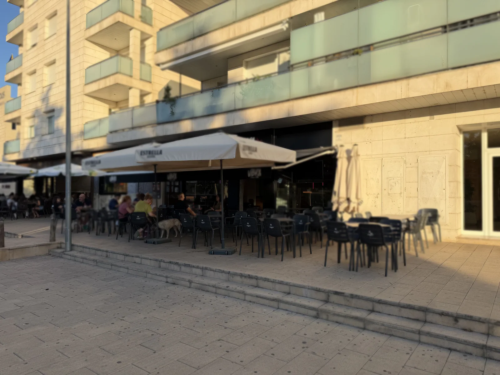 La terraza de Vibra vista desde la calle, con las sombrillas y gente sentada al atardecer