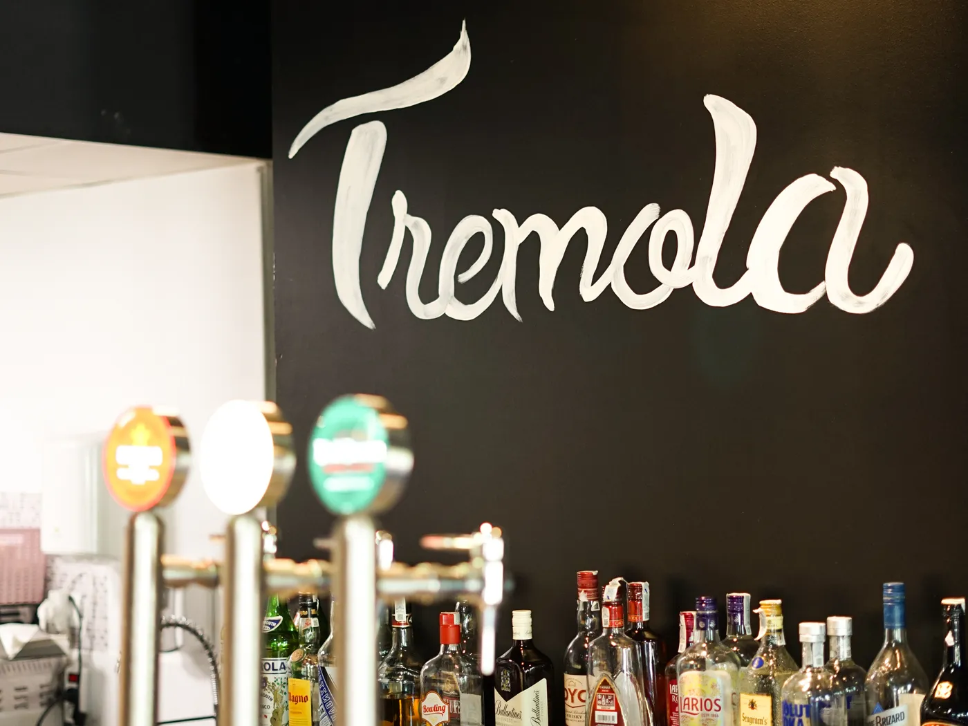La pared negra del Tremola con el nombre pintado a mano, detrás de la barra y los grifos